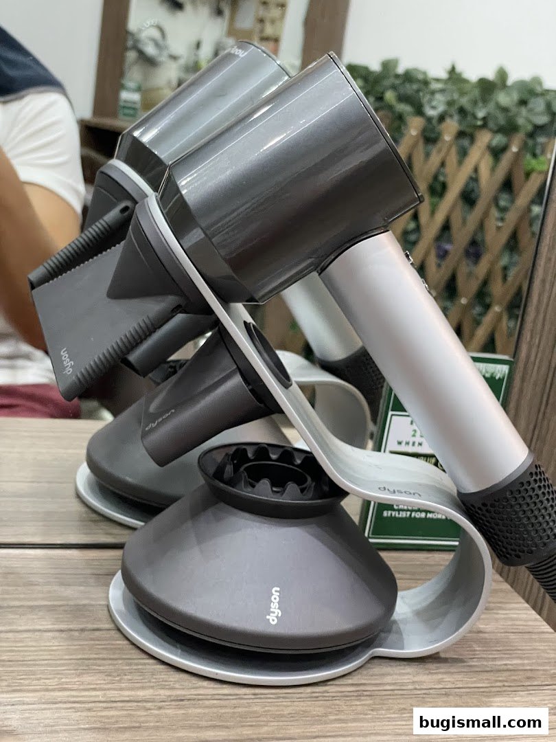 Two Dyson hair dryers displayed on stands in a salon setting.