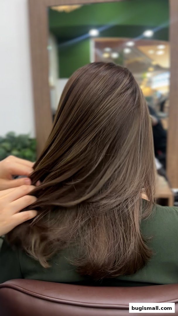 A person's back with beautifully styled brown hair with highlights.