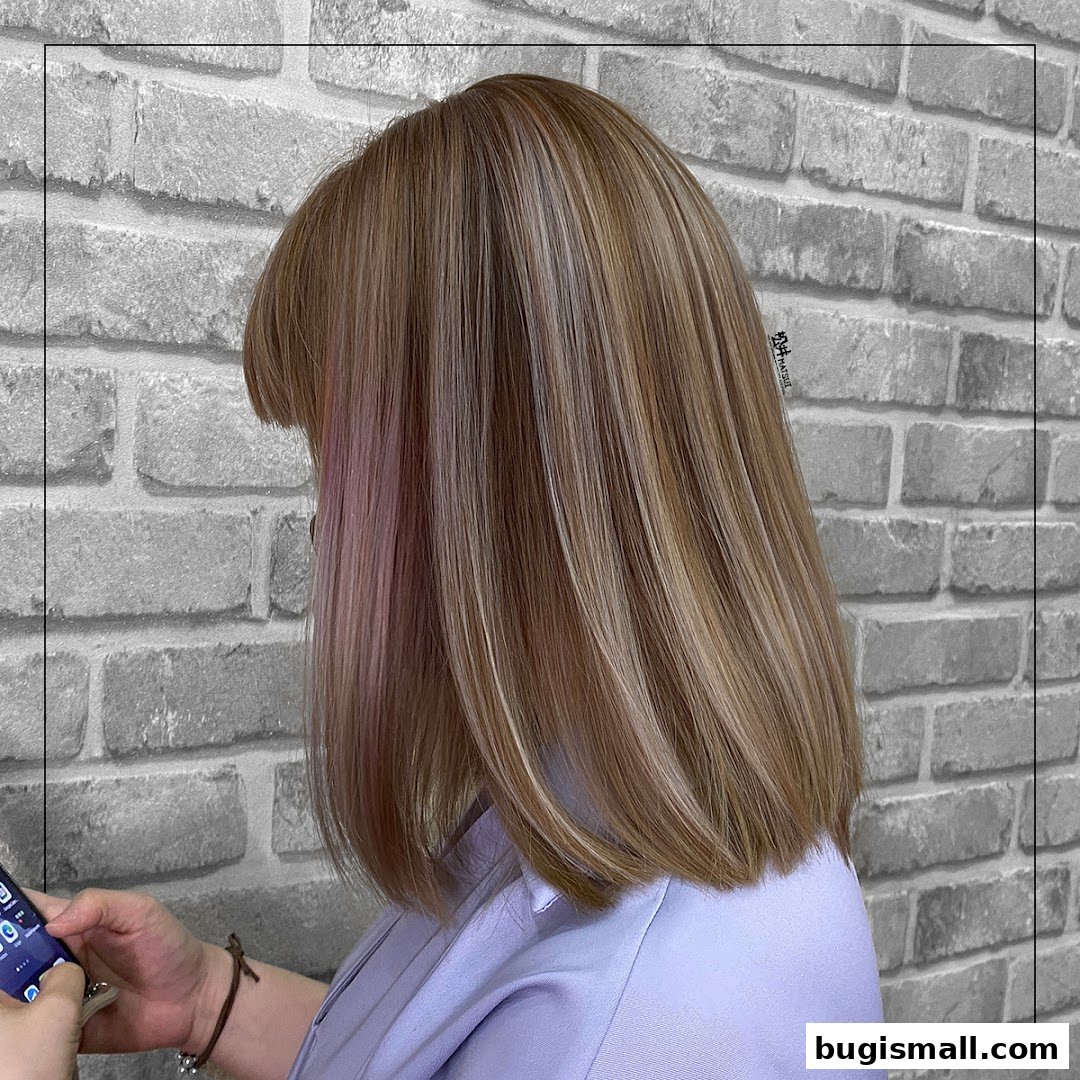 A person with stylish blonde and brown hair with subtle pink highlights.