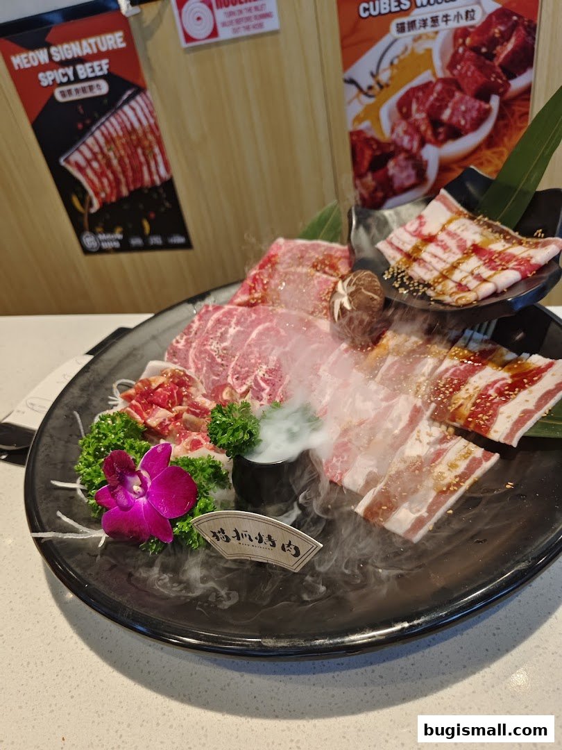 A platter of assorted raw meats, including thinly sliced beef and marbled cuts, garnished with a flower and smoke.
