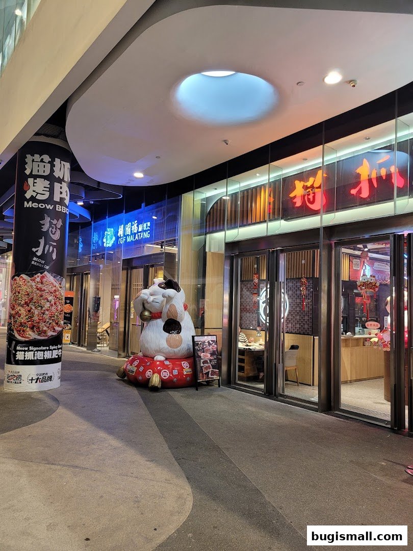 The exterior of Meow Barbecue restaurant with a large Maneki-neko statue outside.