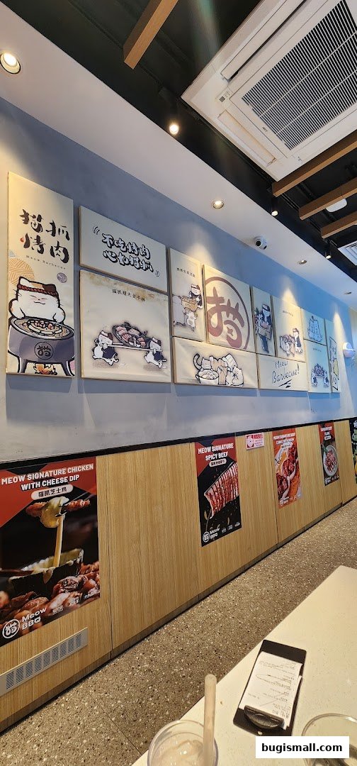 Interior view of Meow Barbecue with cute cat-themed artwork and food posters on the wall.