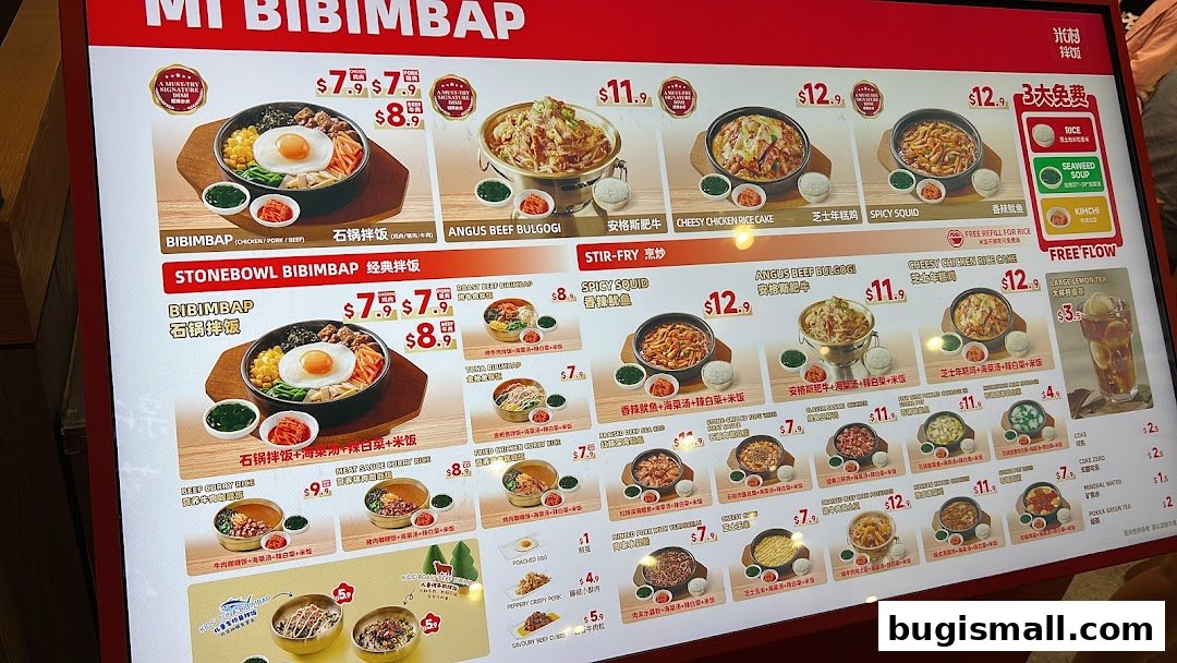 A digital menu board displaying various Korean dishes, primarily bibimbap and stir-fries, with prices.