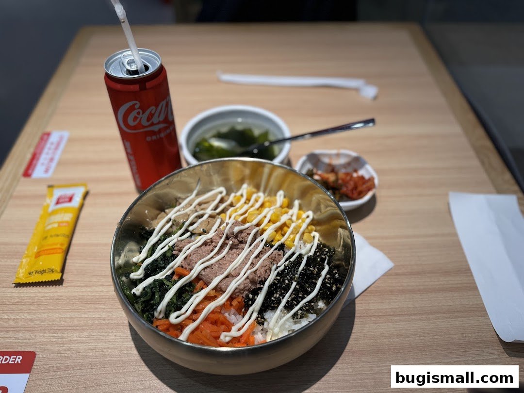 A delicious bibimbap dish with tuna, corn, and vegetables, served with a side of kimchi and a Coca-Cola.