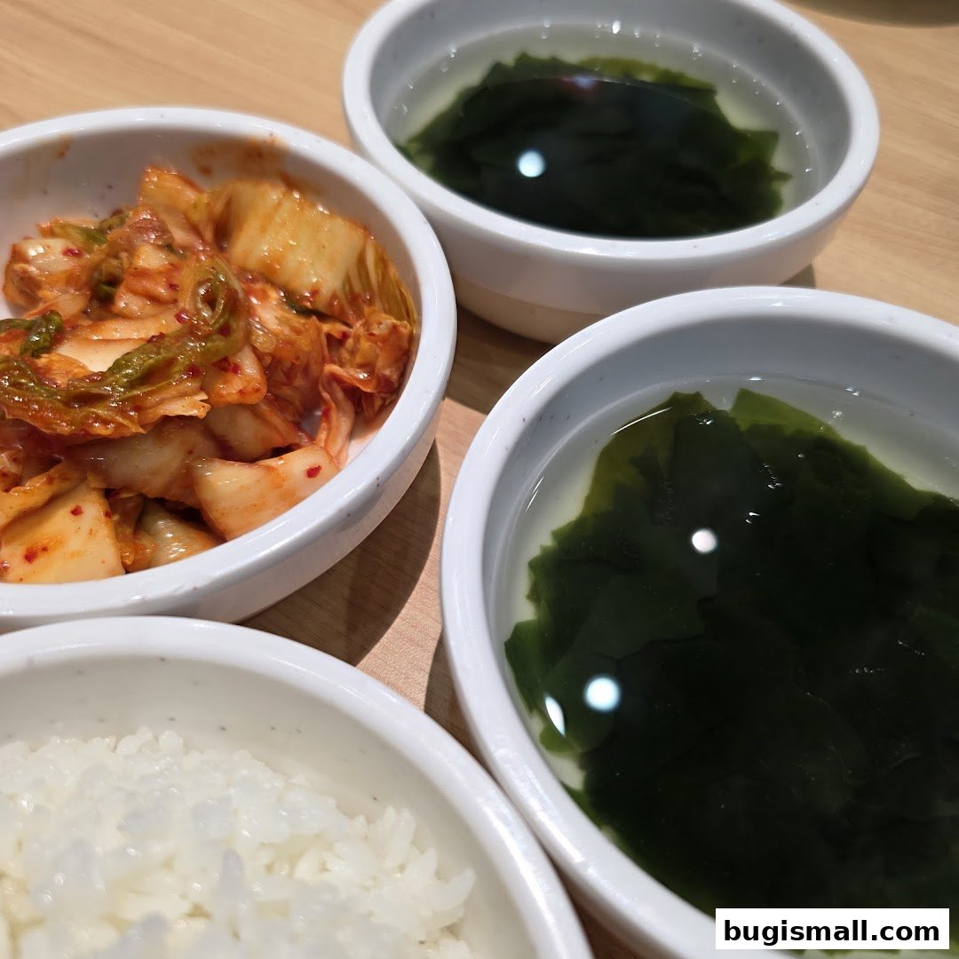A close-up of Korean side dishes including kimchi, rice, and seaweed soup.