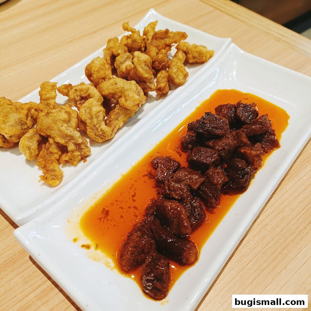 Two white rectangular plates with Korean fried chicken and braised beef in sauce.