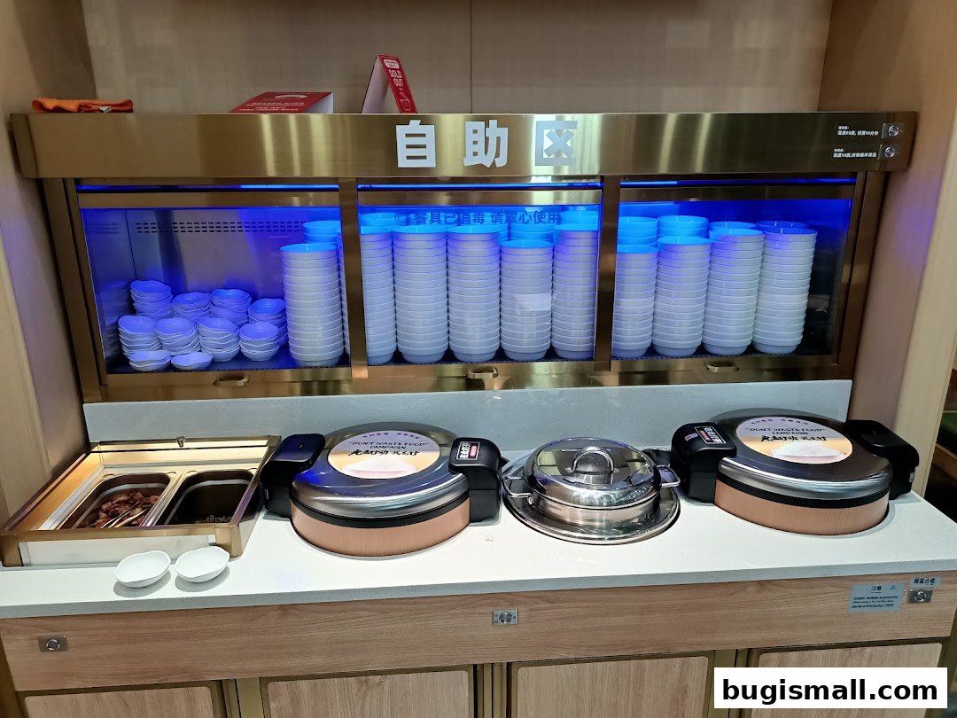 Buffet station with stacks of bowls, serving dishes, and food containers.