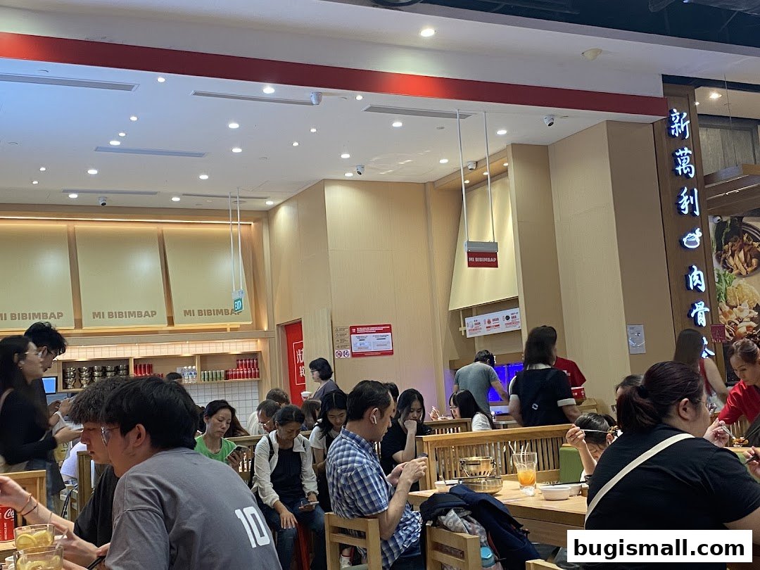 People dining at tables inside a busy Korean restaurant with "MI BIBIMBAP" signage.