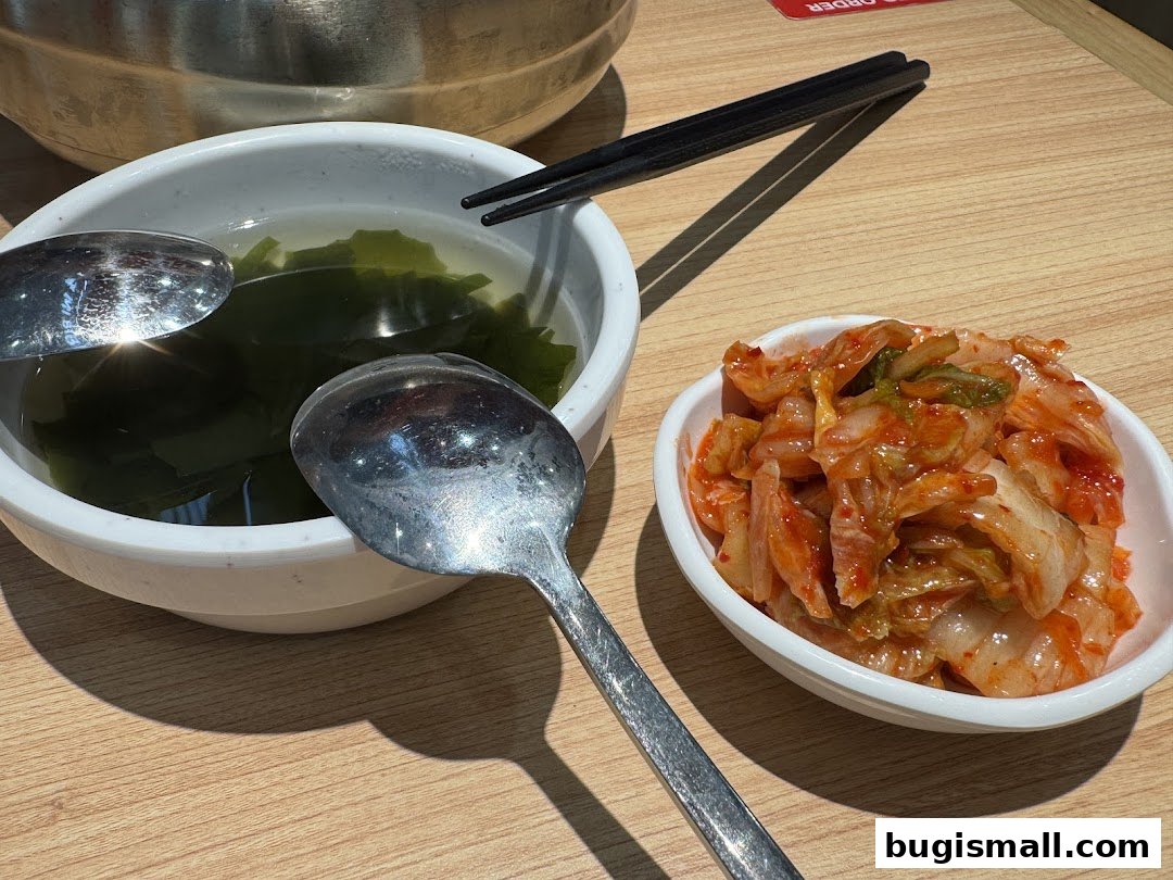 A close-up of Korean side dishes, including kimchi and seaweed soup, with chopsticks.