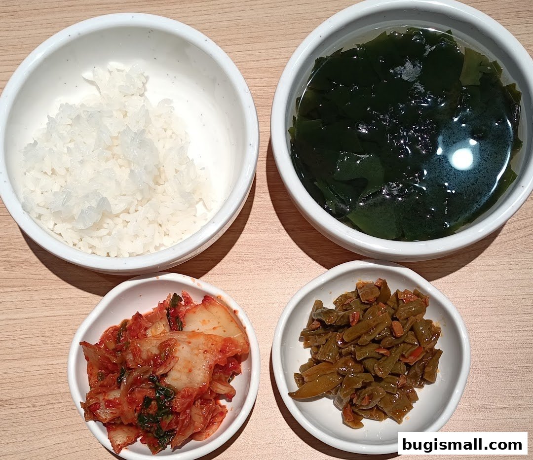 A top-down view of a Korean meal with rice, seaweed soup, kimchi, and pickled vegetables.
