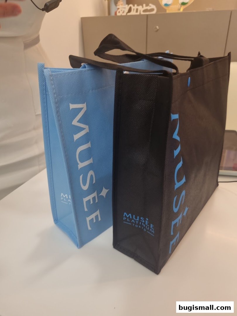 Two reusable shopping bags, one light blue and one black, with the Musee Platinum Tokyo logo.