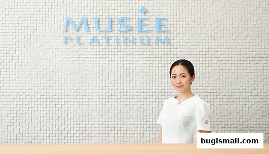 A friendly staff member stands in front of the Musee Platinum logo.
