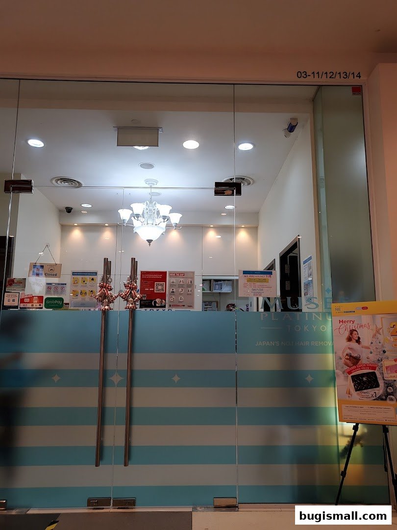 The entrance to Musee Platinum Tokyo, a hair removal salon, with frosted glass doors and a promotional poster.