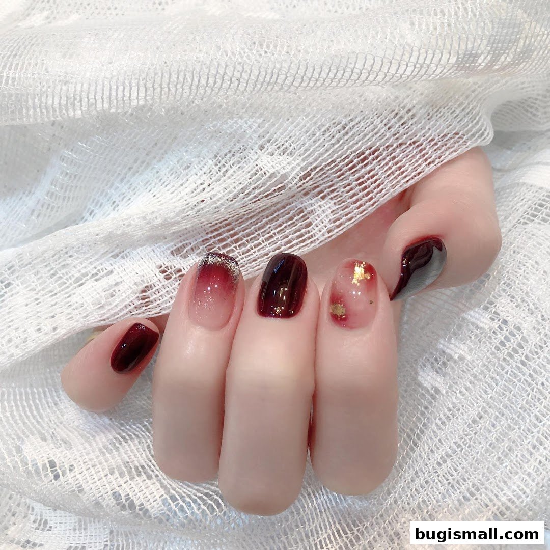 A close-up shot of a hand displaying beautifully manicured nails with a gradient and gold leaf design.