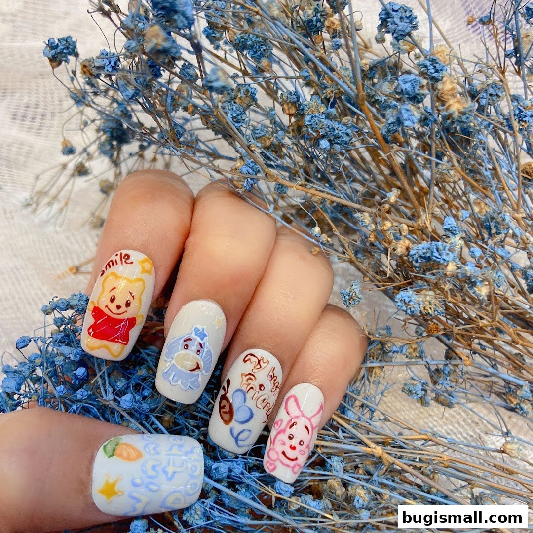 A hand with intricately designed nails featuring cartoon characters and dried blue flowers.