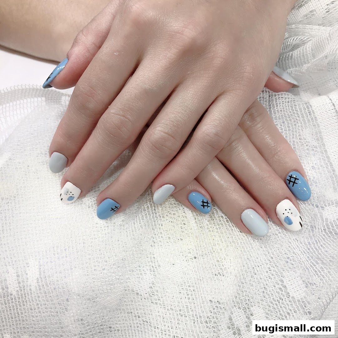 A close-up of hands with stylish light blue, grey, and white nails featuring cute cartoon designs.