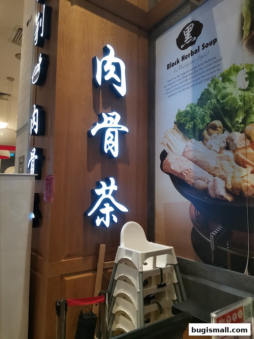 Illuminated Chinese characters for 'Bak Kut Teh' and a poster for Black Herbal Soup.