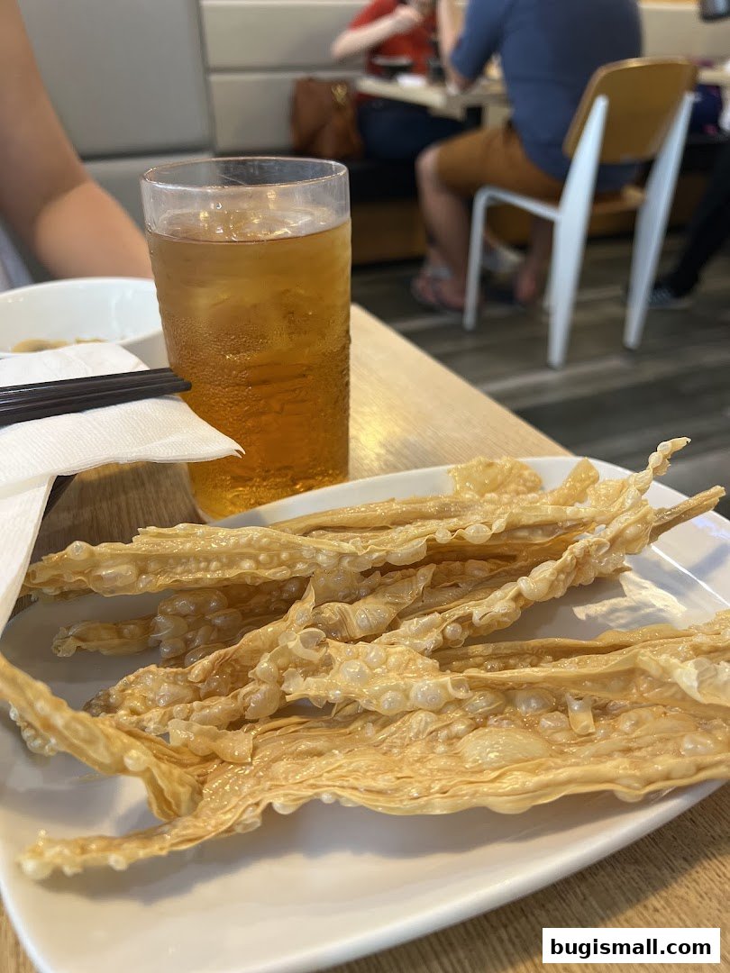 A plate of crispy fried bean curd skin with a glass of iced tea.