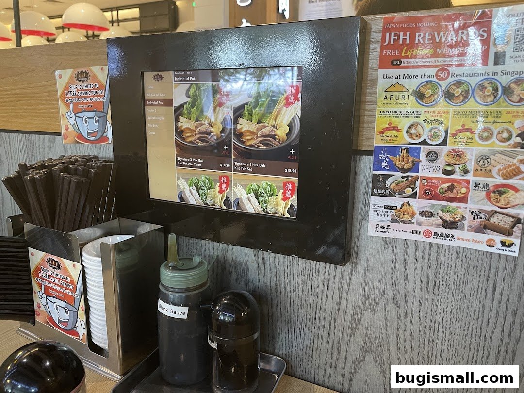 A digital menu displaying Bak Kut Teh dishes and a rewards poster.