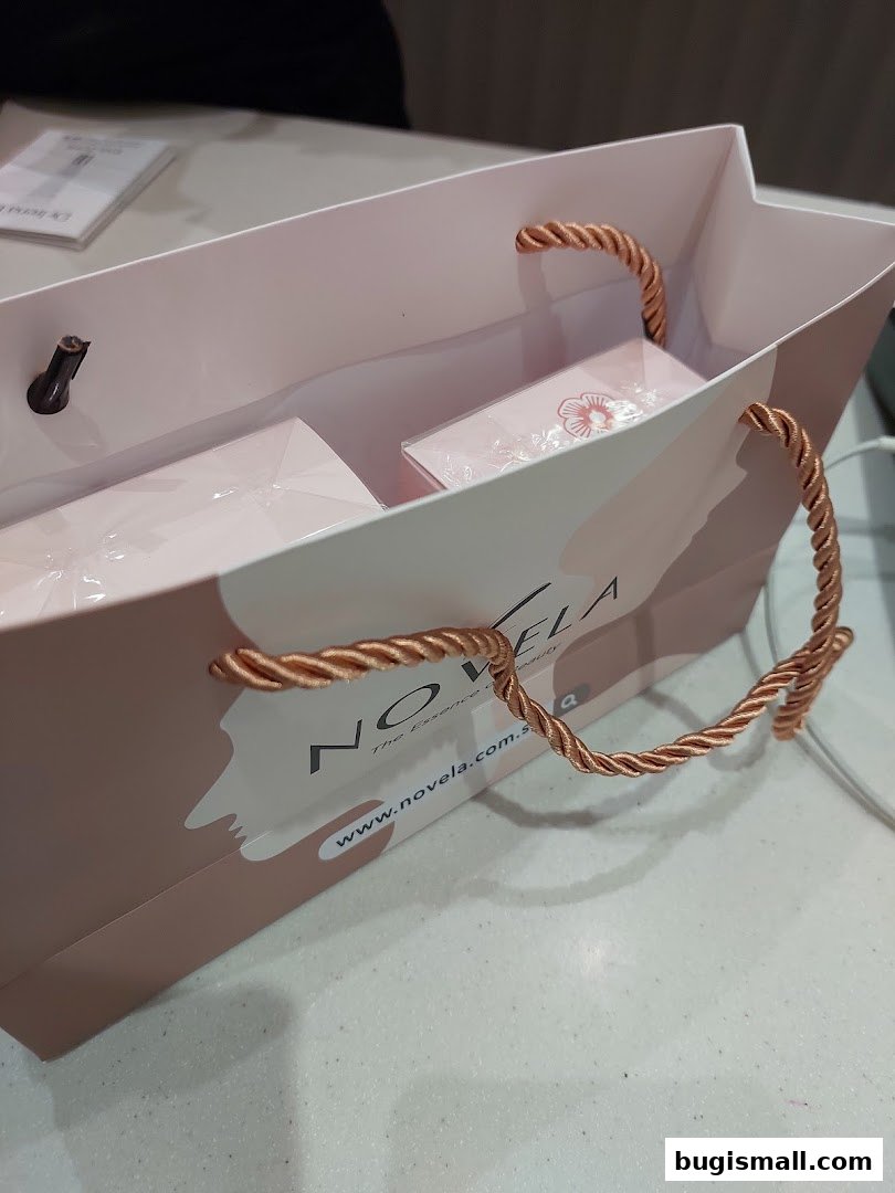 A shopping bag from Novela with products inside, featuring the brand's logo and website.