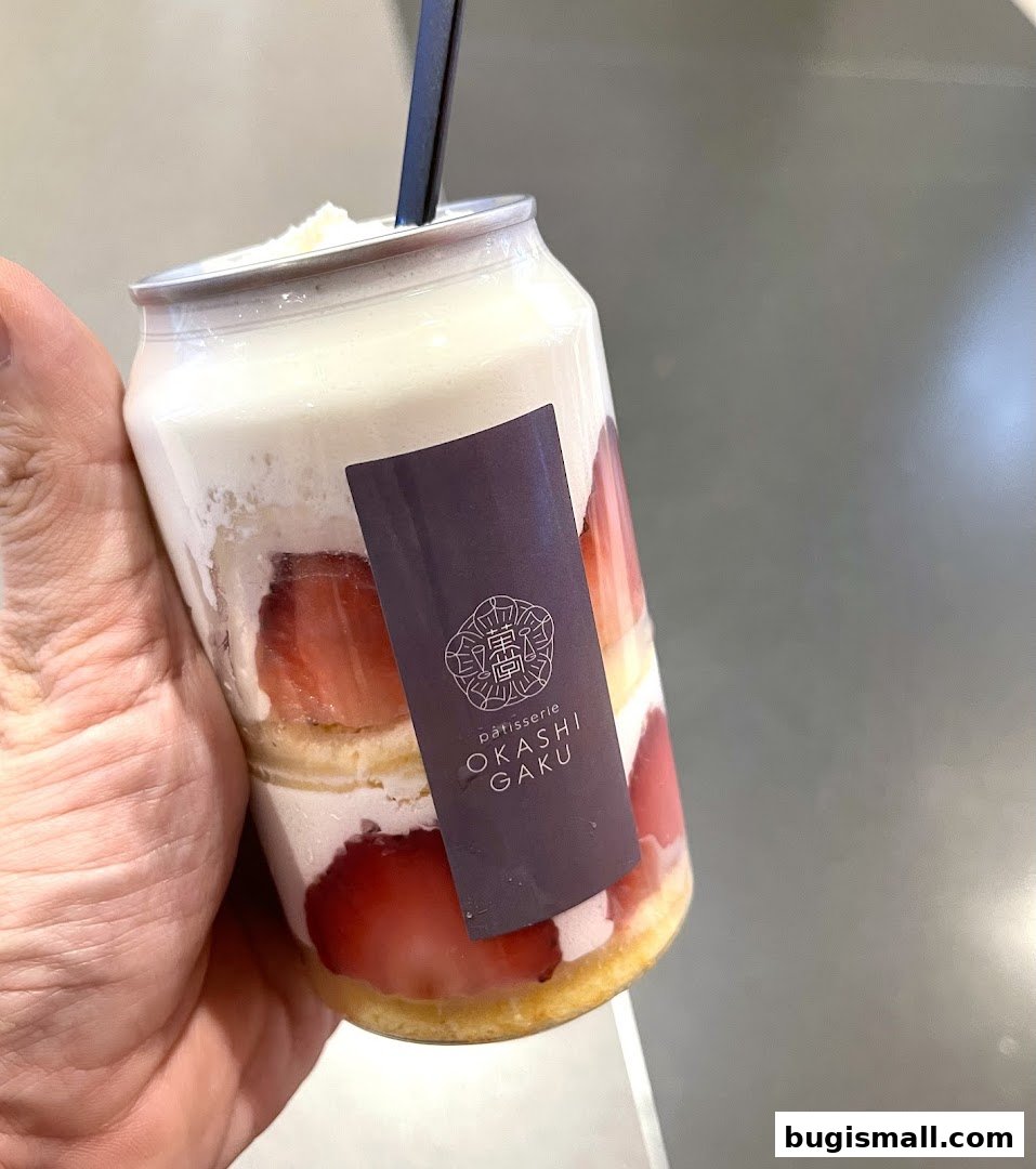 A hand holds a strawberry cake dessert in a can from Okashi Gaku.