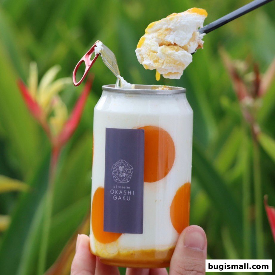 A hand holds a can of dessert with orange slices and cream, topped with a spoonful of dessert.