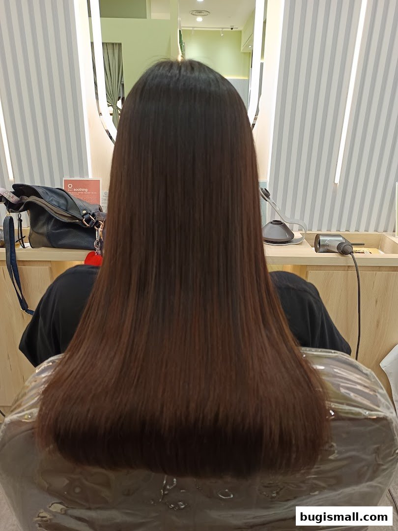 A person with long, straight, brown hair sitting in a salon chair.