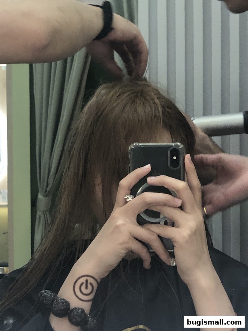 A person is getting their hair styled with a hairdryer in a salon.