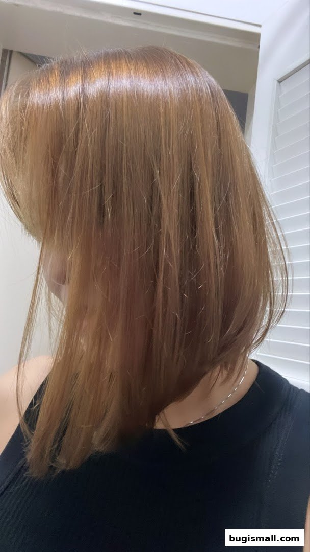 A person with a fresh, glossy, medium-length bob haircut in a warm, reddish-brown shade.