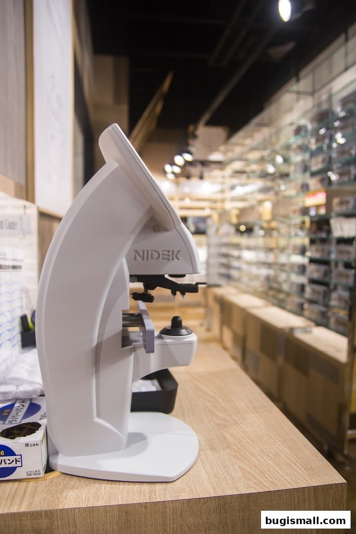 A close-up of an optical device with the NIDEK logo, in a brightly lit eyewear store.