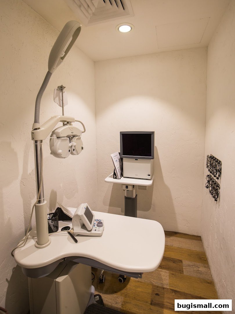 An eye examination room with optical equipment and a wall-mounted display.