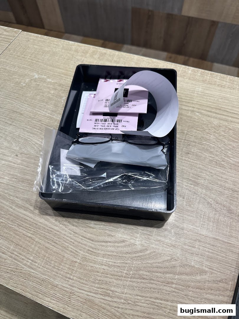 A pair of black-rimmed glasses and receipts in a black tray on a wooden table.