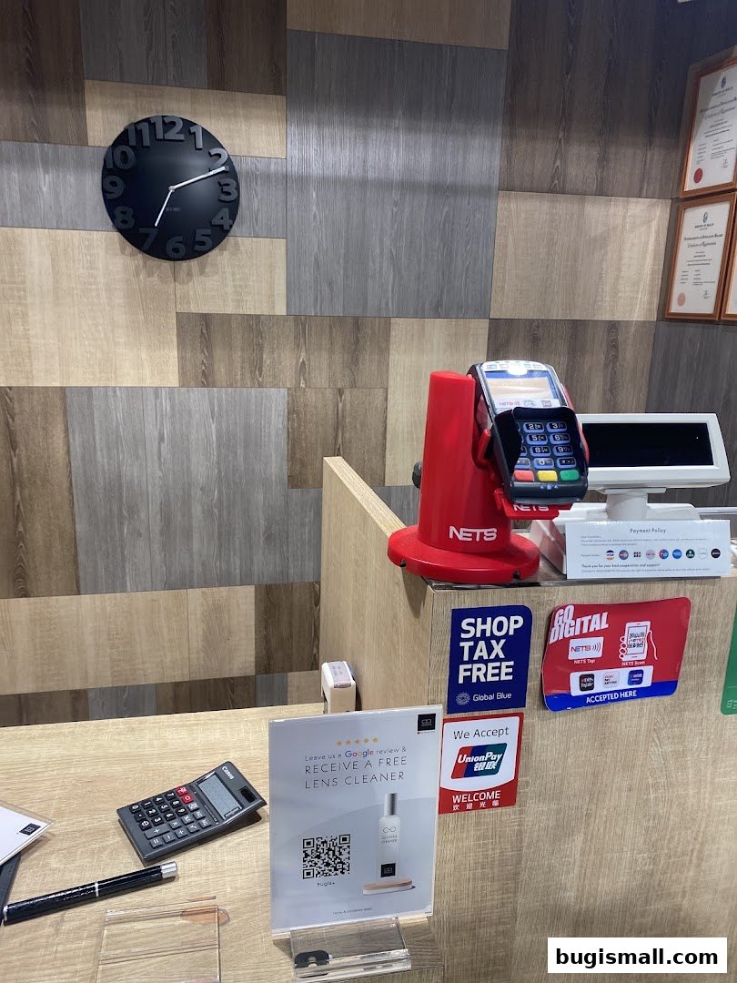 A shop counter with a clock, payment terminal, calculator, and promotional signs.