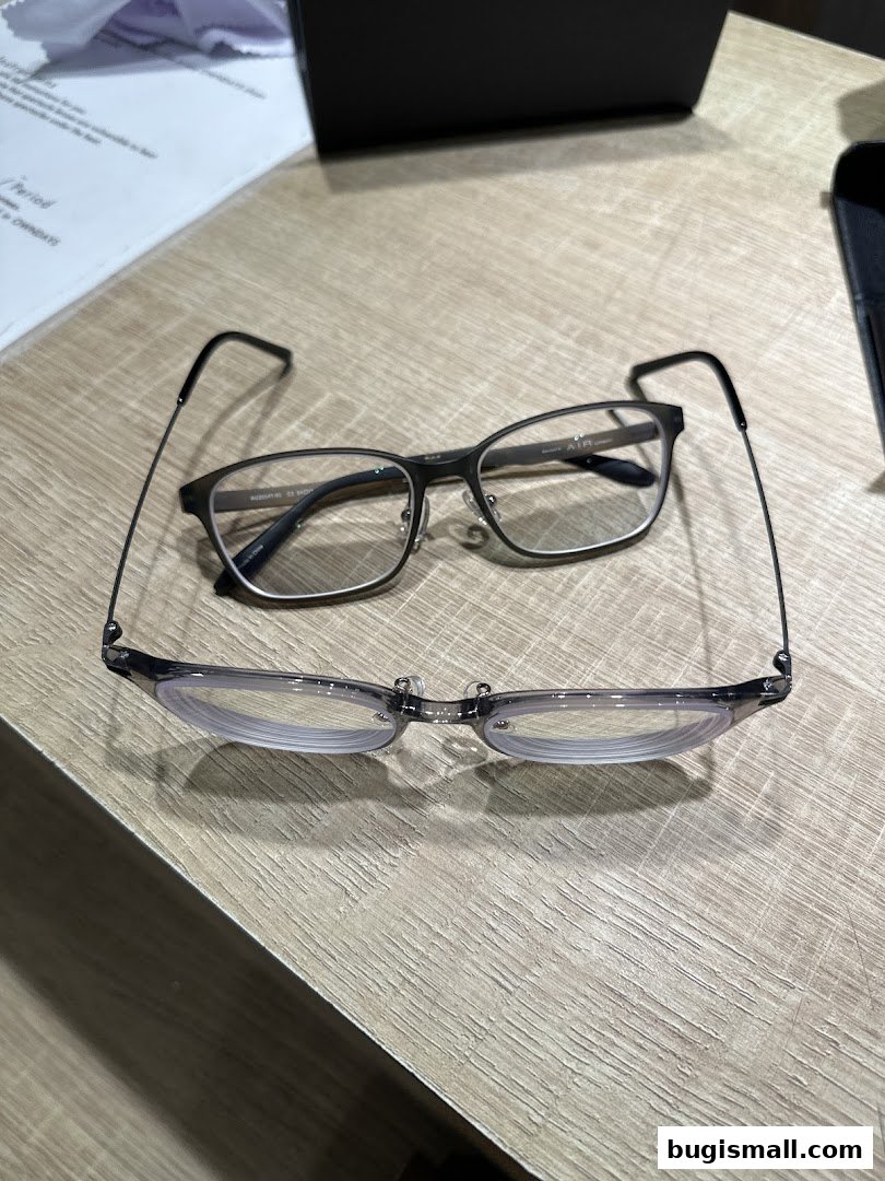 Two pairs of stylish eyeglasses are displayed on a wooden surface.