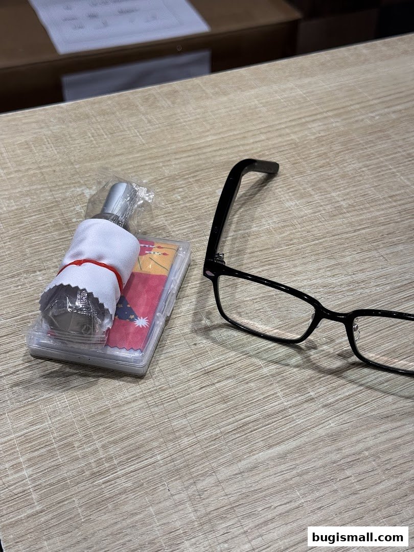 A pair of black-rimmed glasses and an eyeglass cleaning kit on a wooden surface.