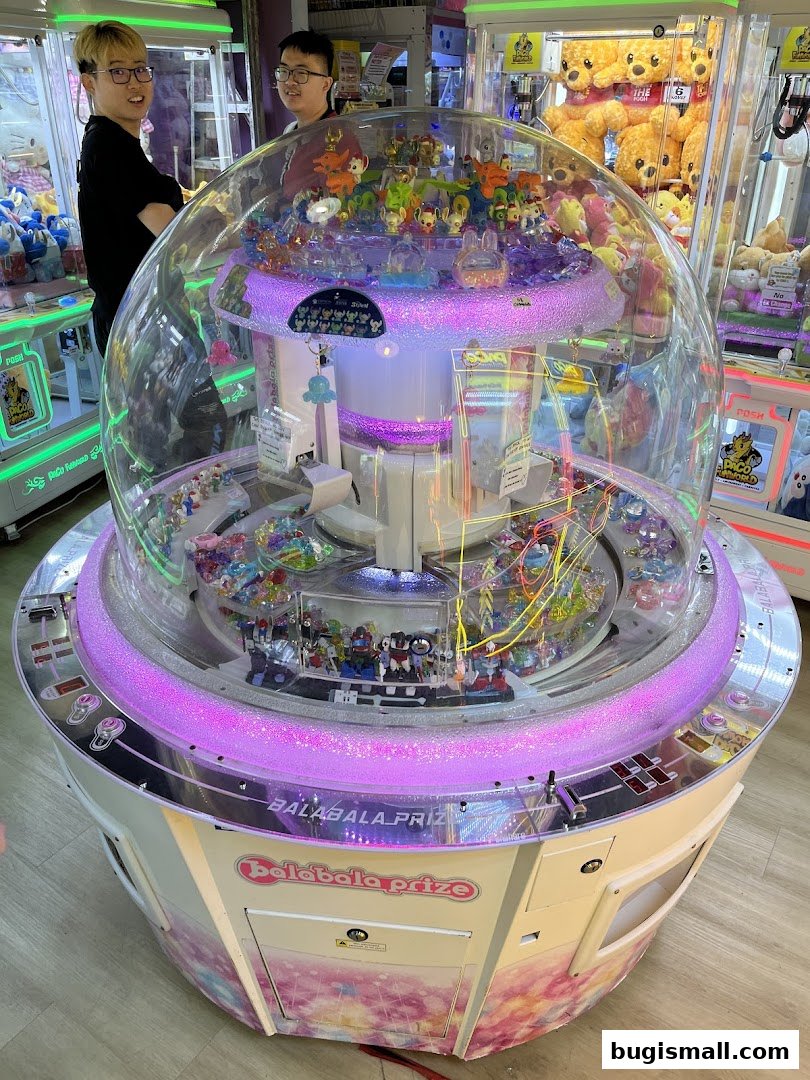 A colorful prize claw machine filled with toys, with two people standing nearby.