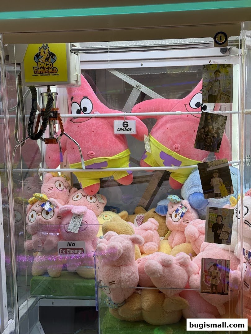 A claw machine filled with various plush toys, including large Patrick Star figures.