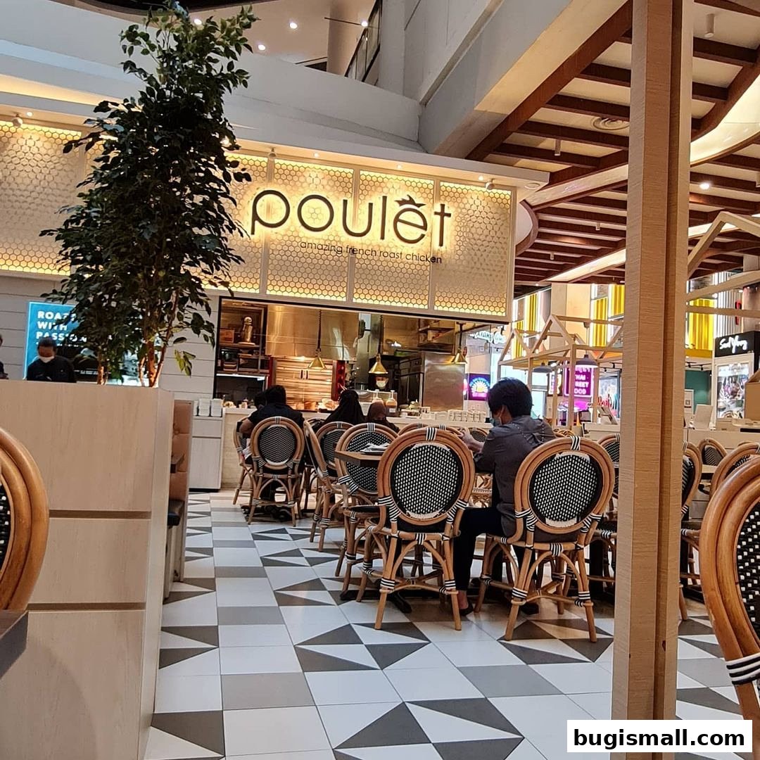 Interior of Poulet restaurant with diners seated at tables and the restaurant's sign visible.