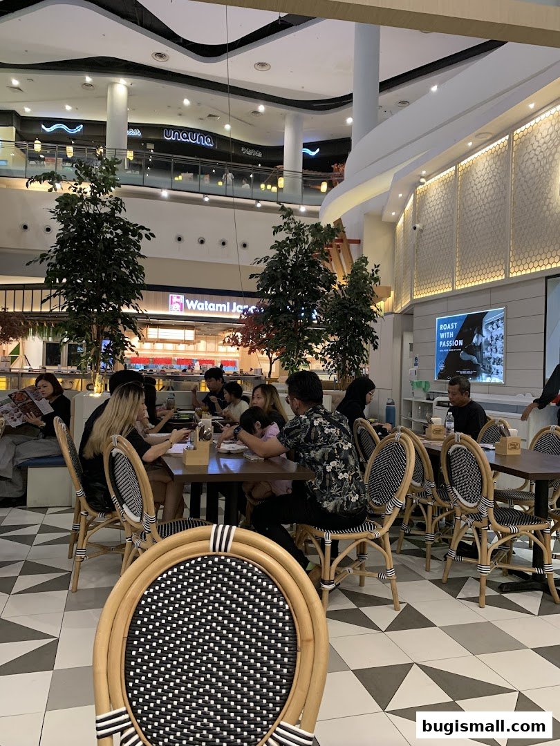 Diners enjoying a meal at tables inside a modern restaurant with stylish chairs.