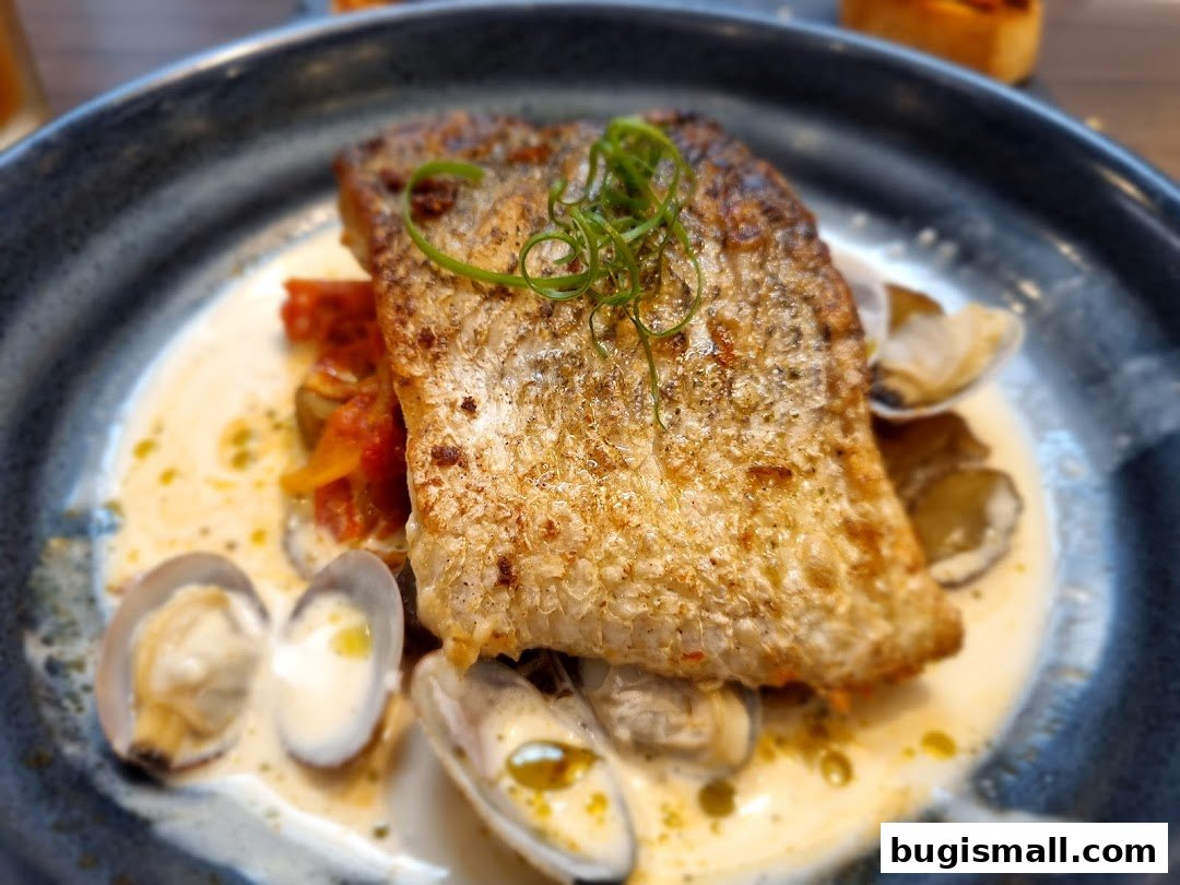 A close-up of a perfectly cooked fish fillet served with clams and a creamy sauce.