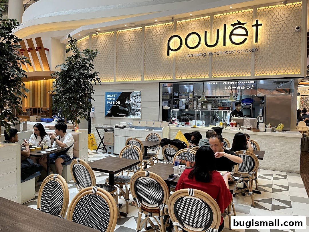Interior of Poulet restaurant with diners seated at tables and the kitchen visible.