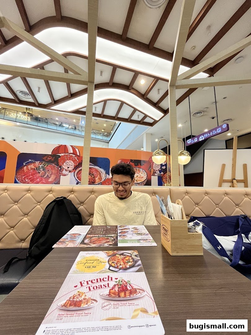A man sits at a table in a restaurant, looking at menus with food pictures.
