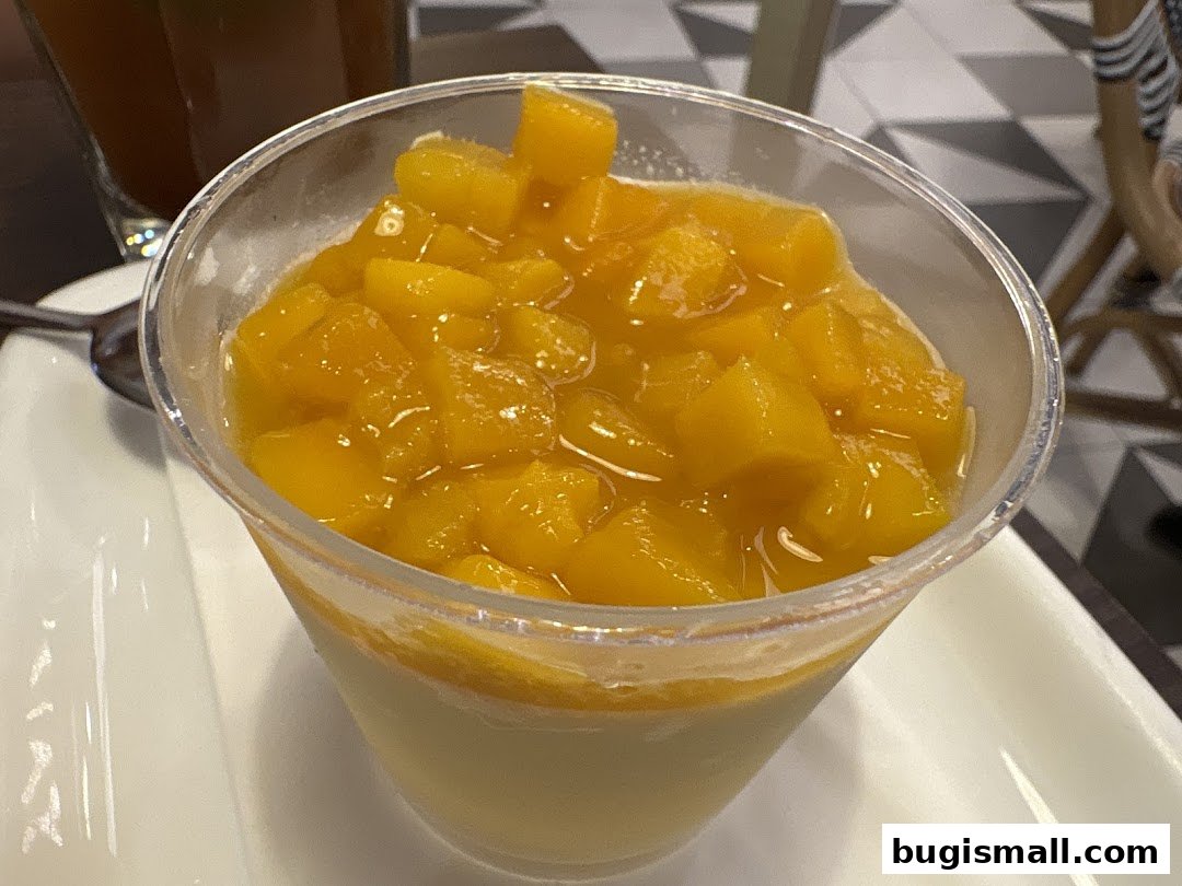 A close-up of a dessert cup filled with diced mango and a creamy base.