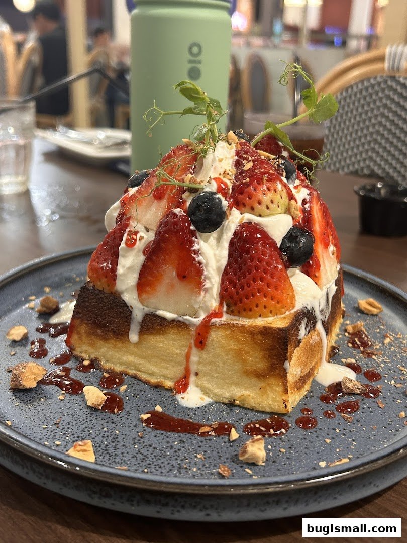 A decadent slice of toast topped with whipped cream, strawberries, blueberries, and nuts.