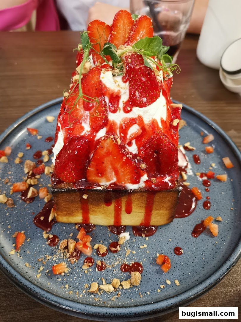A decadent dessert featuring a slice of toast topped with whipped cream, strawberries, and a strawberry sauce.