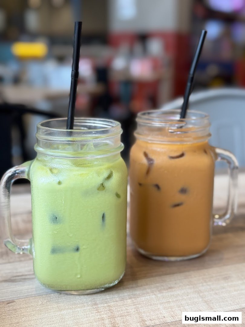 Two refreshing iced drinks, one green and one milky tea, served in mason jars with straws.