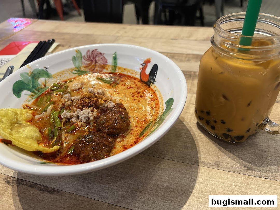 A bowl of flavorful noodle soup with a side of Thai iced tea with boba.