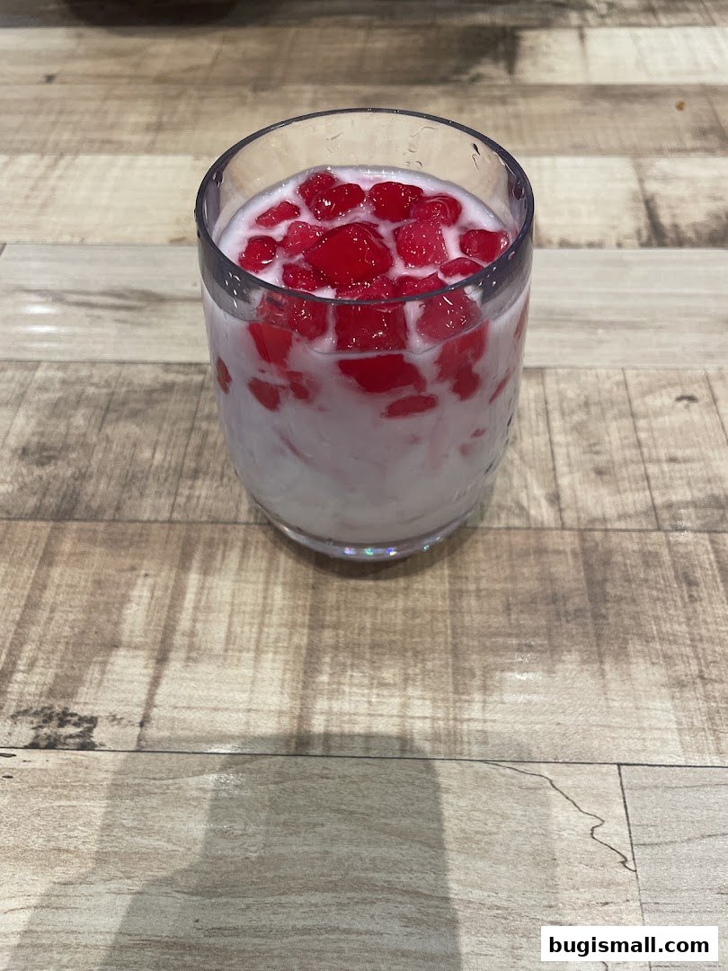 A refreshing glass of Thai dessert with red water chestnuts in coconut milk.