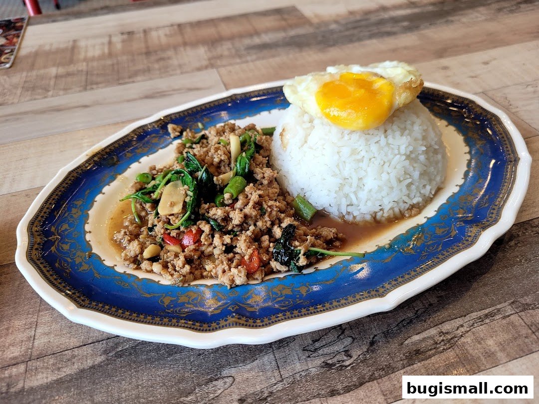 A plate of Thai basil stir-fry with minced meat, served with rice and a fried egg.