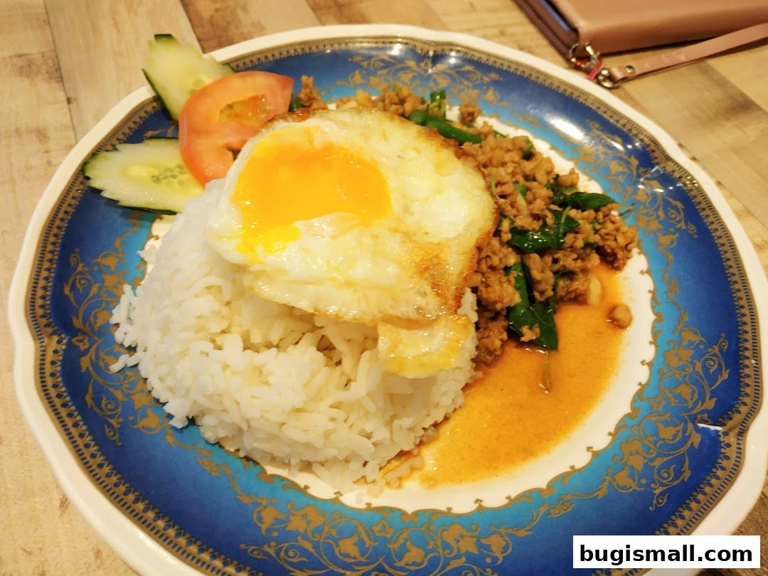 A plate of Thai basil stir-fry with minced meat, rice, and a fried egg.